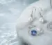 Freshwater pearl earrings, blue gemstone ring, and silver necklace arranged on pearl-white stone